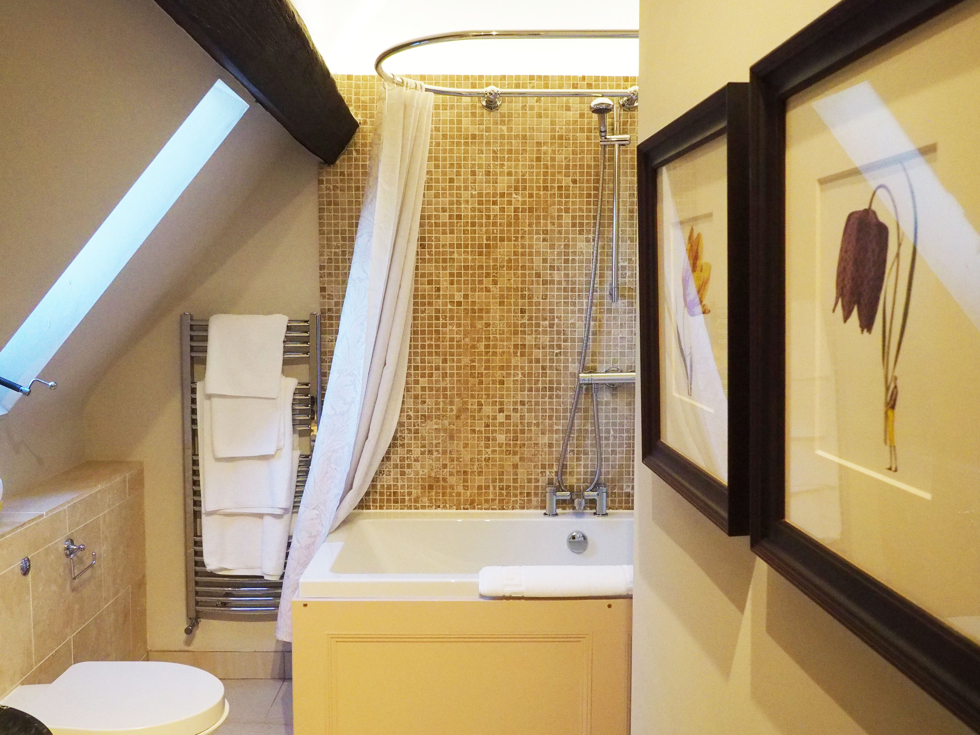 Un baño con bañera, inodoro, toallero y cortina de ducha.