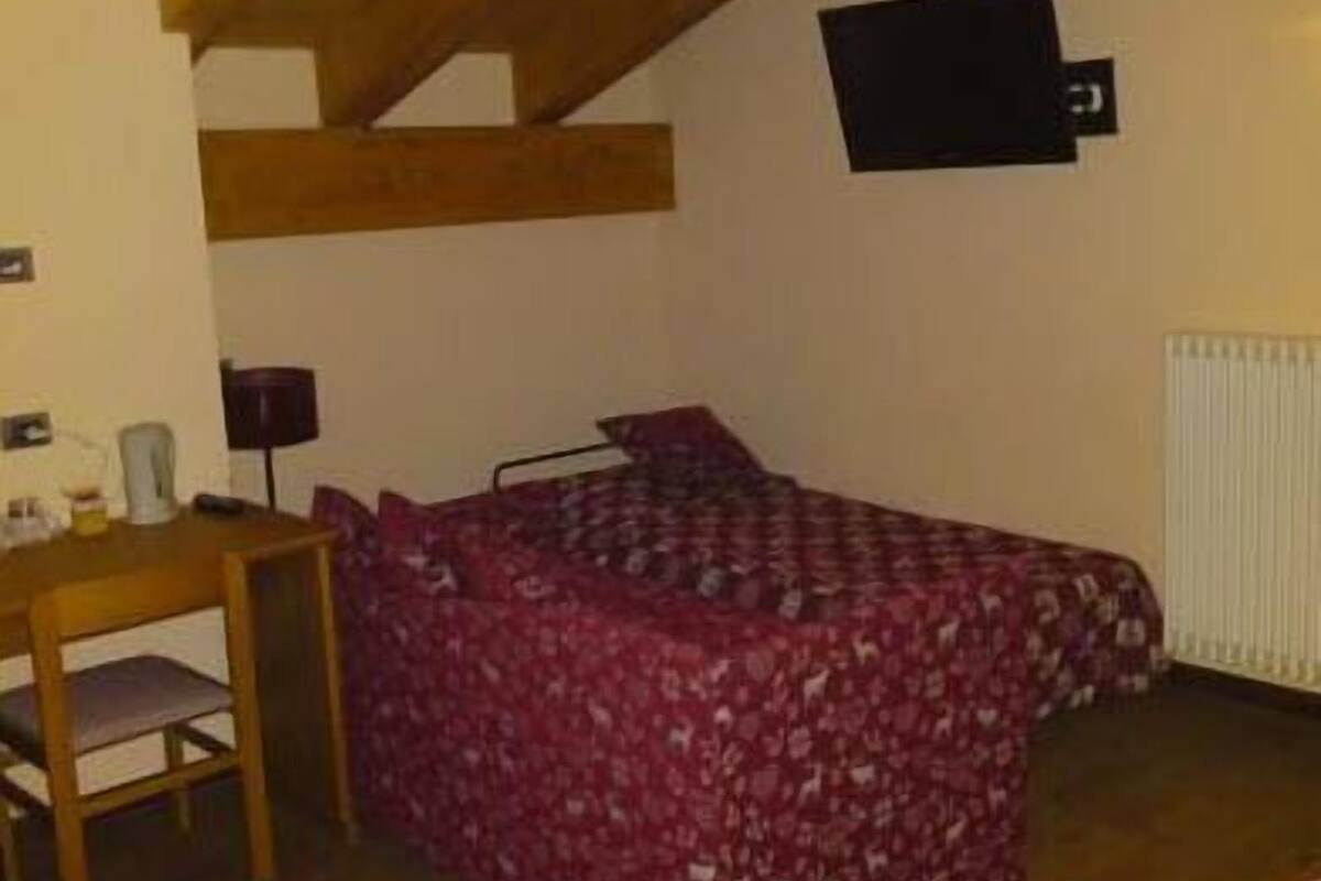 Un dormitorio con cama, escritorio y radiador.