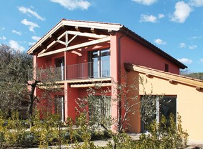 A two-story house with a red facade, a balcony with metal railings, and a clear blue sky in the background. - Relais Campiglioni (Montevarchi)
