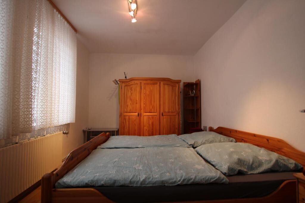 A bedroom with two beds, a wooden wardrobe, and a radiator.