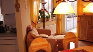 Un salon confortable avec un canapé, deux fauteuils, une table sur laquelle se trouve un panier de fruits et une lampe.