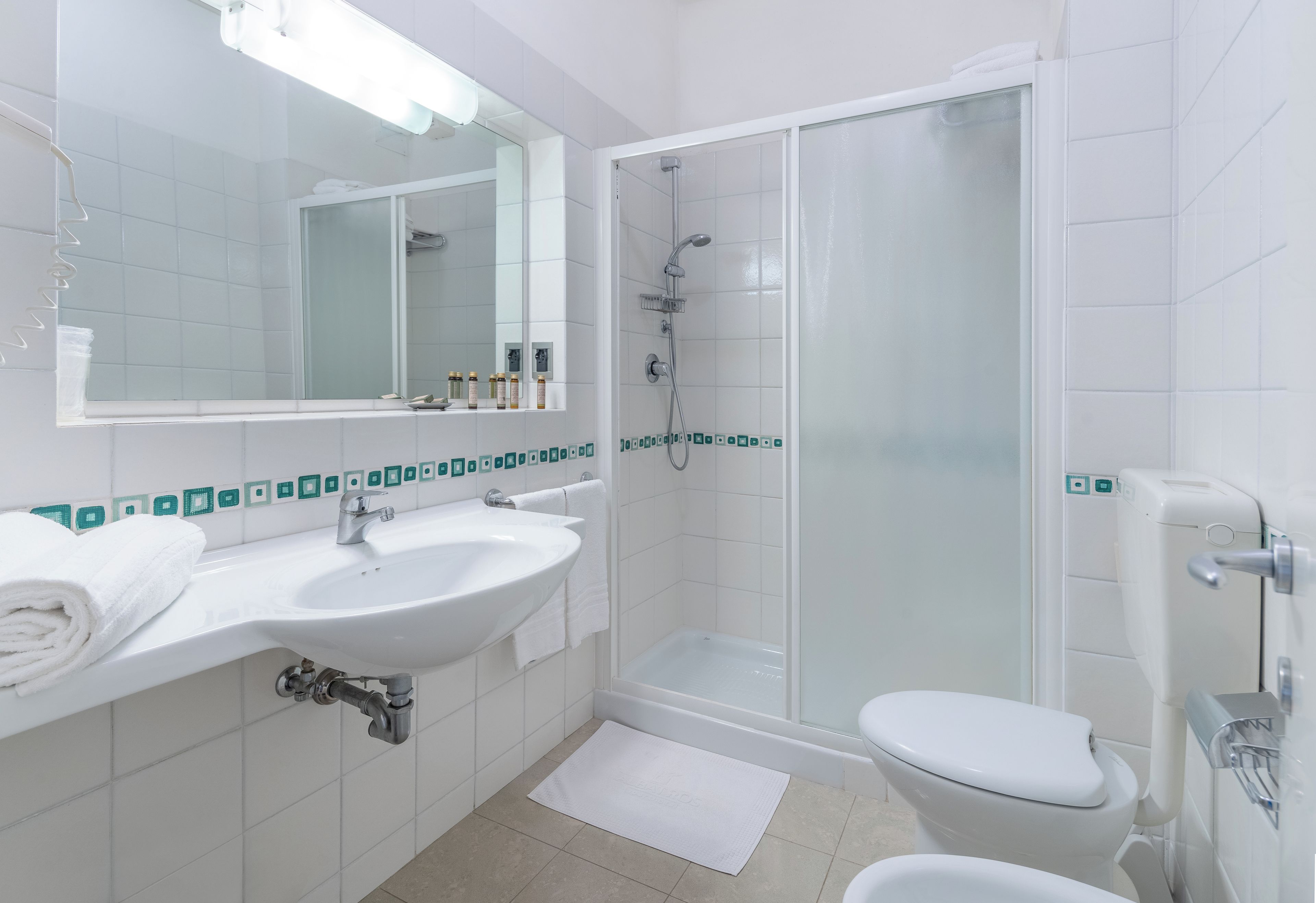 A modern bathroom with a white sink, mirror, and toilet.