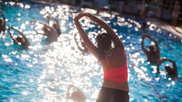 A person stretching in a swimming pool with others in the background.