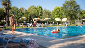 Relax by the pool surrounded by comfortable lounge chairs and shaded umbrellas.