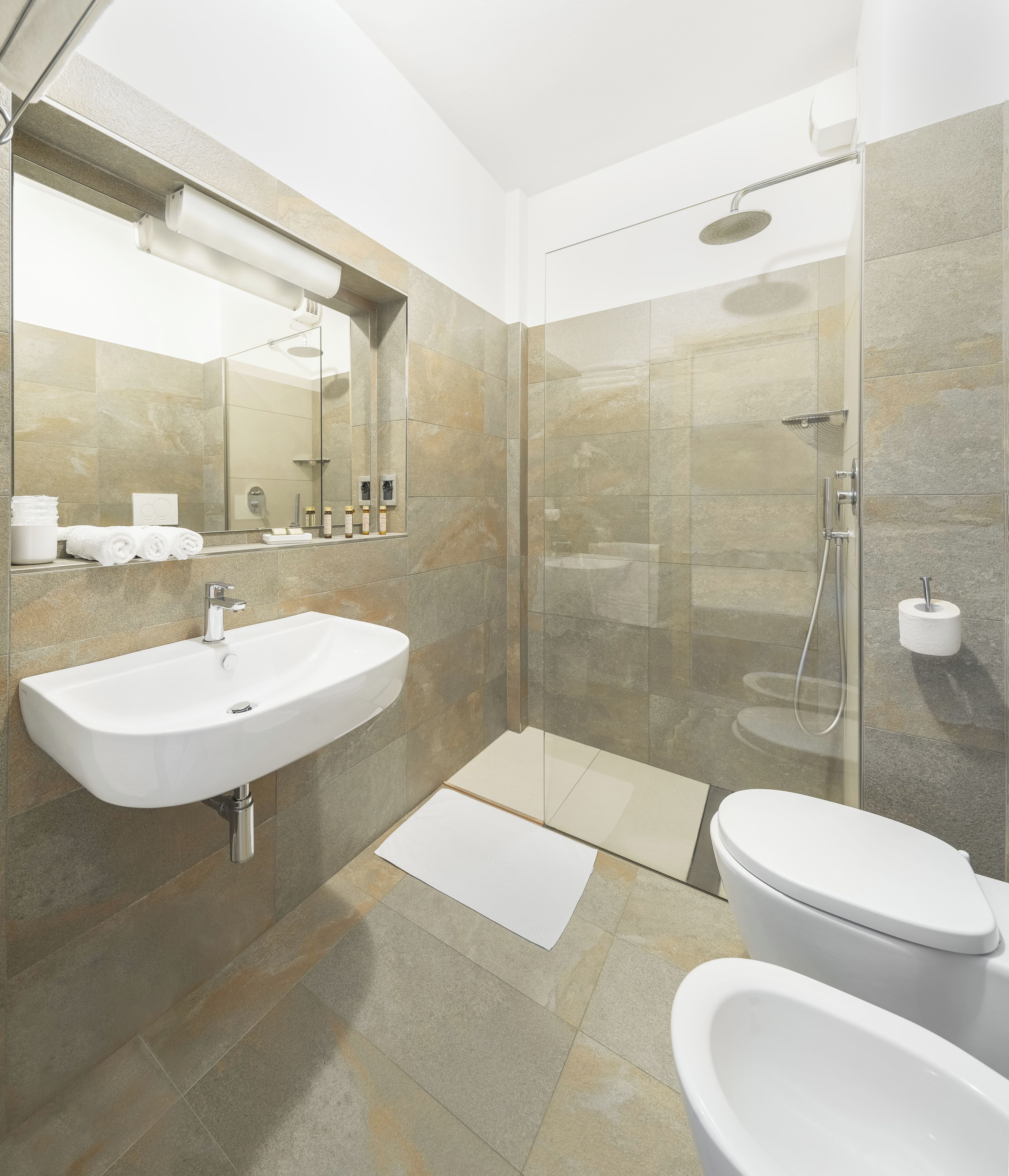 Un baño moderno con un lavamanos independiente, un inodoro y cabina de ducha con paredes de vidrio.