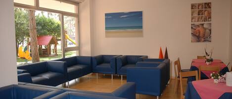Una habitación con sofás azules, una mesa con mantel rosa y un cuadro de una playa.