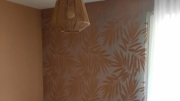 Une chambre à coucher avec un lit, un luminaire suspendu, une table de chevet et une fenêtre avec des rideaux.