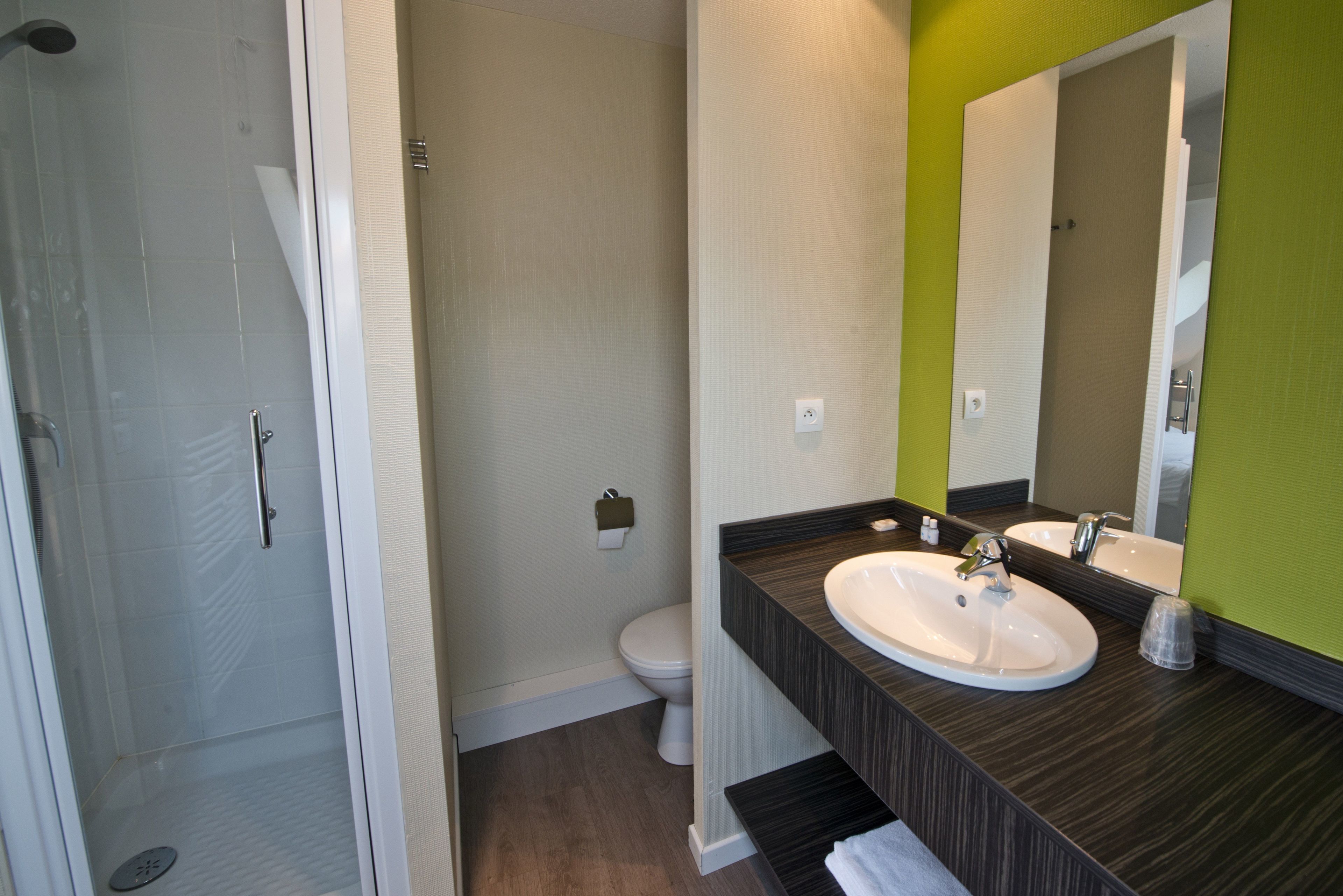 Un baño moderno con ducha, dos lavamanos y un inodoro.