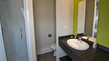 Un bagno moderno con doccia, due lavandini e il water.