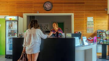 Zona de recepción con pared de madera, un reloj, un refrigerador y mostrador con diversos artículos.
