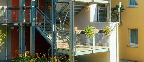 Une structure métallique à plusieurs niveaux, dotée d’escaliers, de balcons et de jardinières.