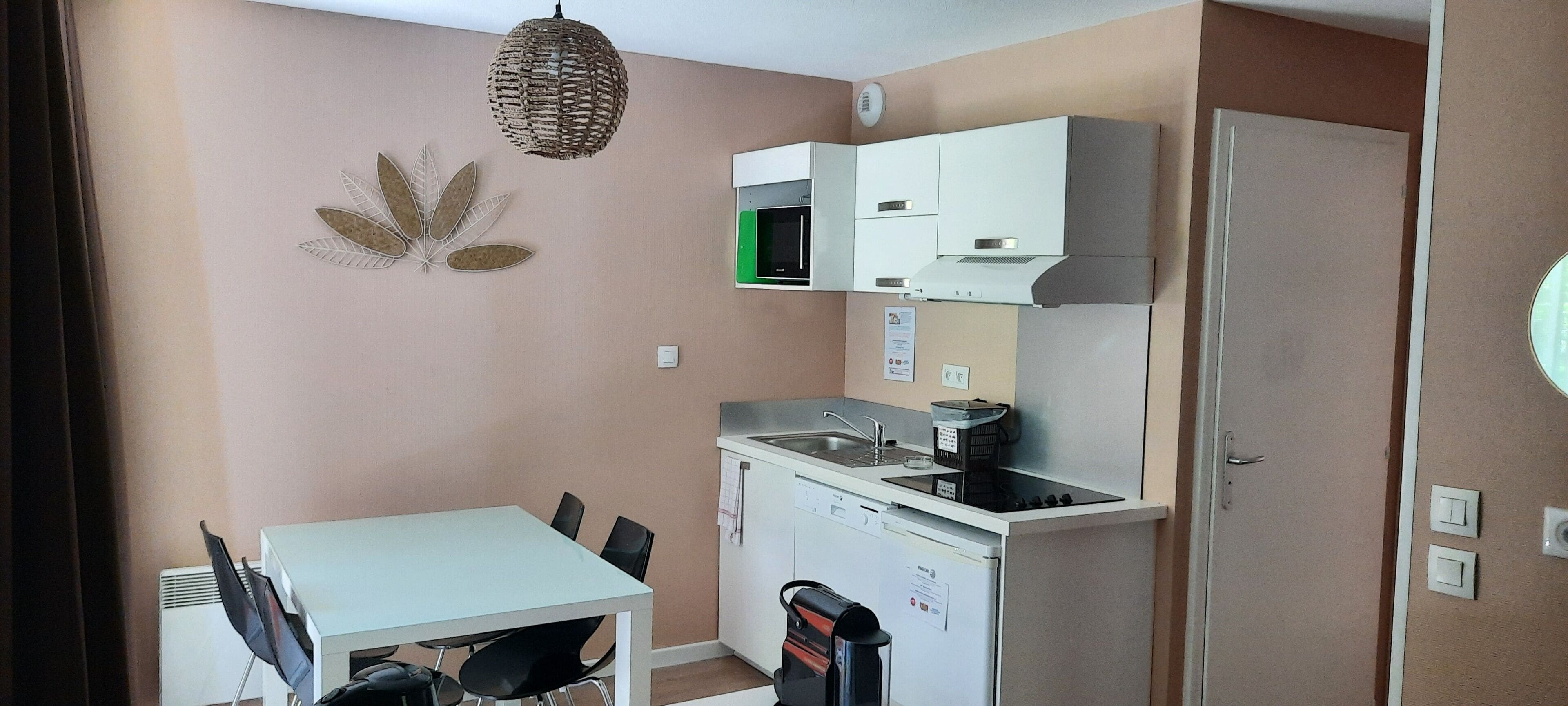 A compact kitchen with a white table and chairs, a microwave, a stove, and a refrigerator.