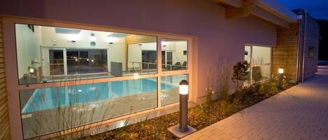 A modern building with large windows overlooking a swimming pool.