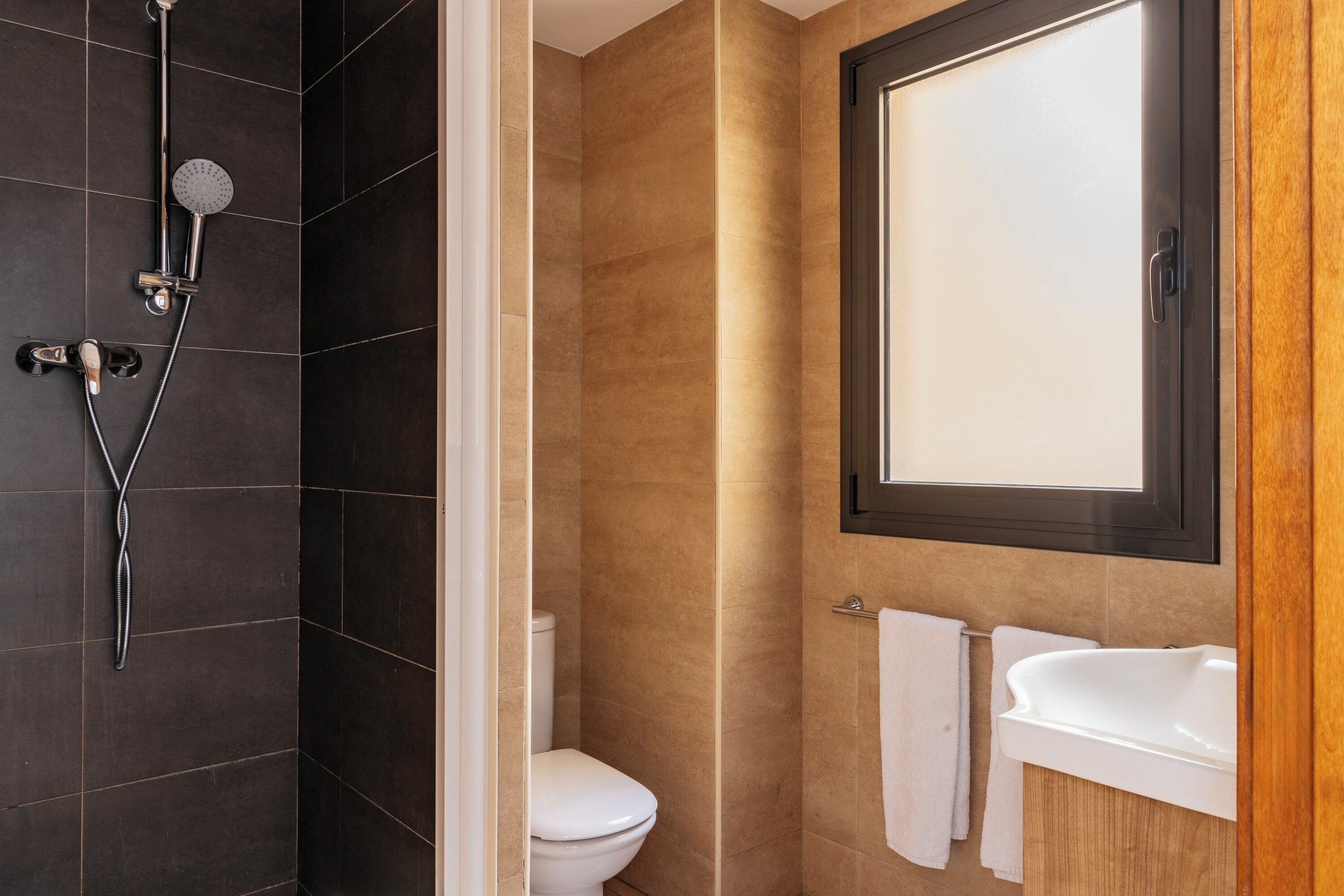 Een badkamer met een douche, toilet en wastafel.