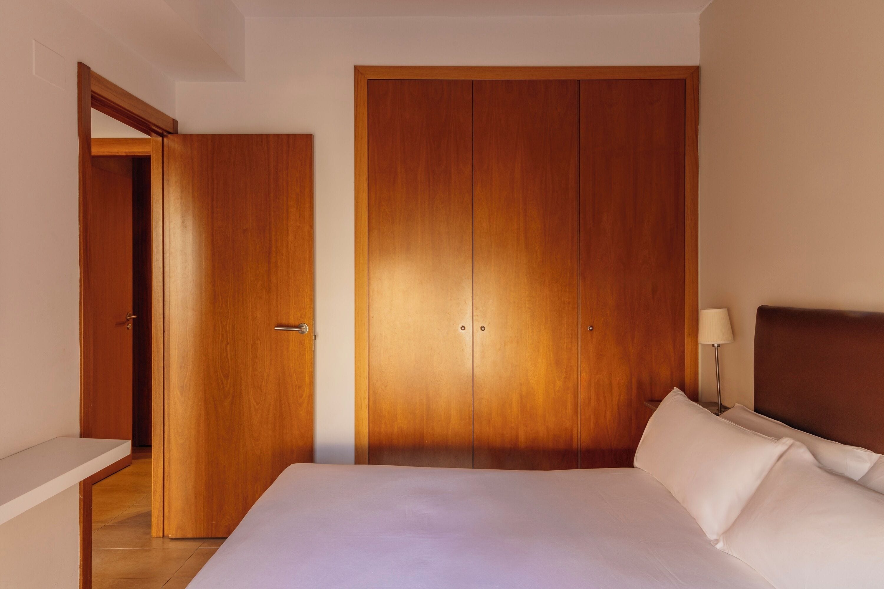 Ein Schlafzimmer mit einem großen Bett, einem Holzschrank und einem Nachttisch mit Lampe.