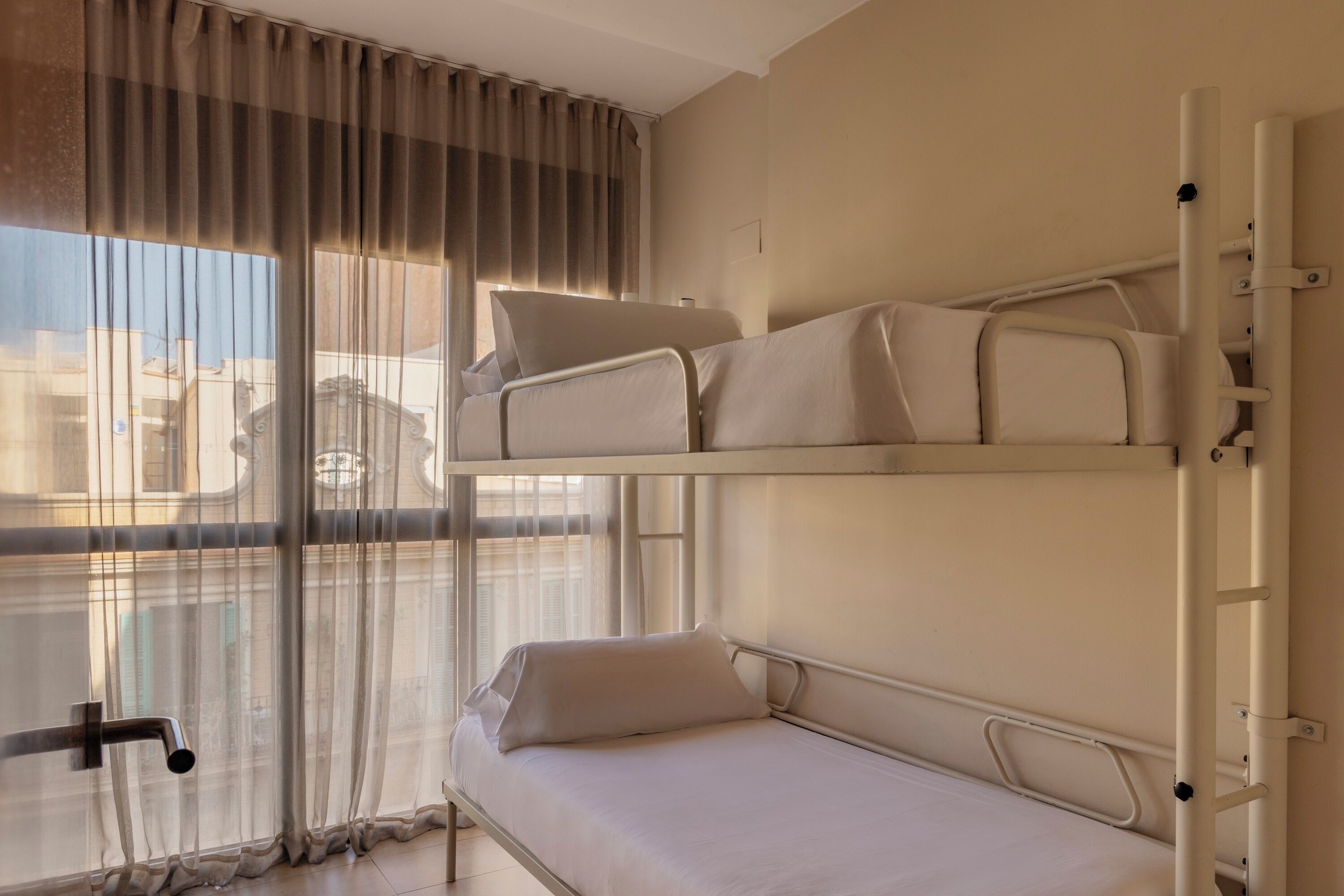 A bunk bed with a window view, curtains, and a metal railing.