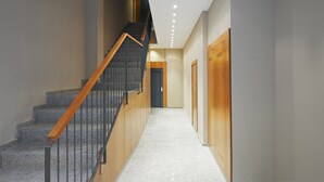 A modern interior with a staircase, wooden doors, and a hallway leading to a door. - Gran de Gràcia Apartments (Barcelona)