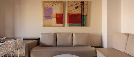 En moderne stue med sofa, sofabord og to abstrakte malerier på væggen.