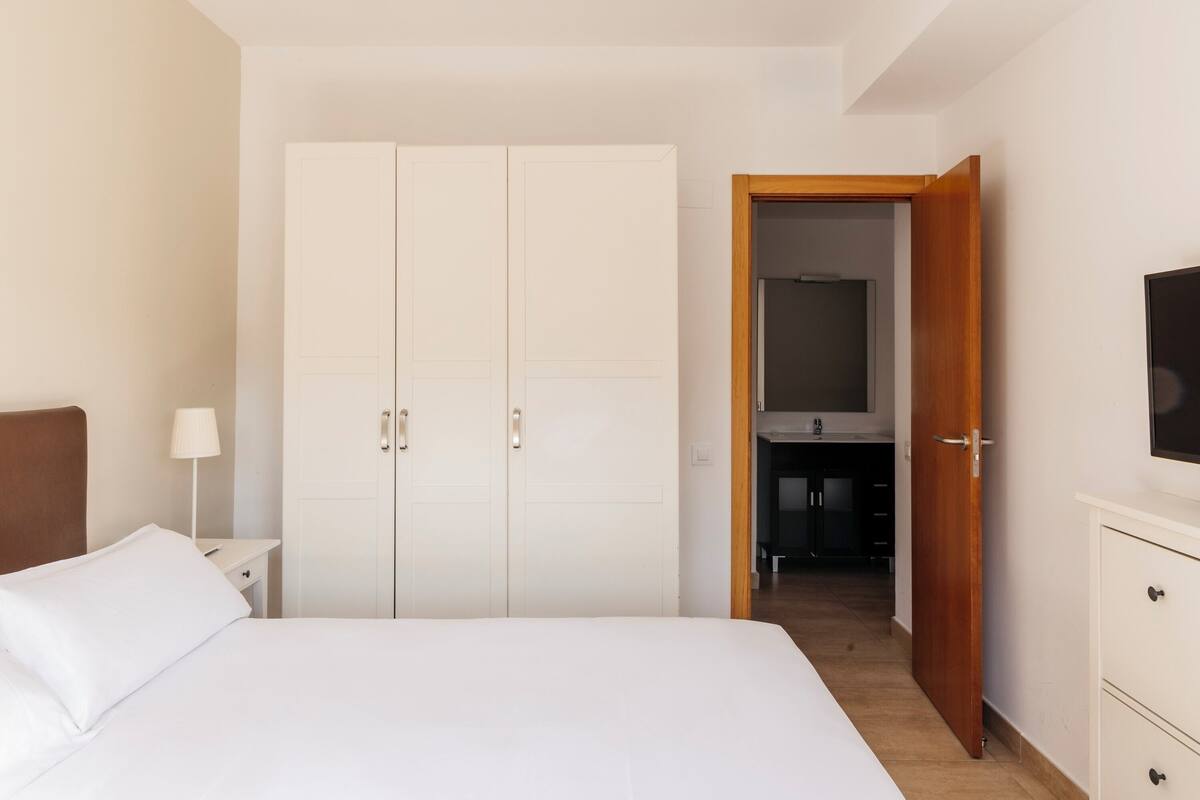 Une chambre à coucher comprenant un lit, une armoire, une table de chevet, une lampe et un téléviseur.