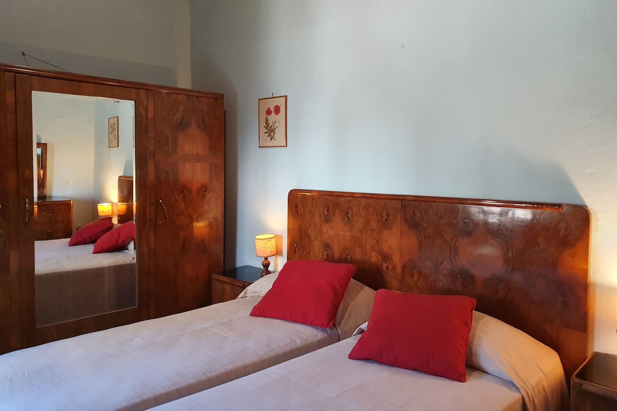 Ein Schlafzimmer mit einem hölzernen Kopfteil, einem großen Spiegel und zwei roten Kissen.
