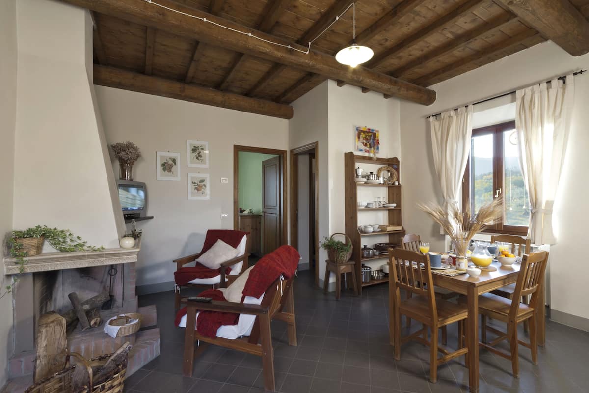 Ein gemütliches Wohnzimmer mit Kamin, Holzmöbeln und einem Essbereich mit Tisch für zwei Personen.
