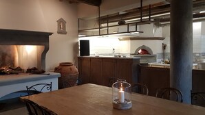 A rustic kitchen with a fireplace, wooden cabinets, and a stone oven. - Castello di Pratelli (Figline e Incisa Valdarno)