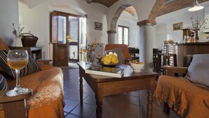 A cozy living room with a fireplace, a dining table, and a comfortable seating area. - Castello di Pratelli (Figline e Incisa Valdarno)