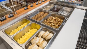 A buffet with various food items including scrambled eggs, biscuits, and different meats. - Wood River Inn & Suites (Hailey)