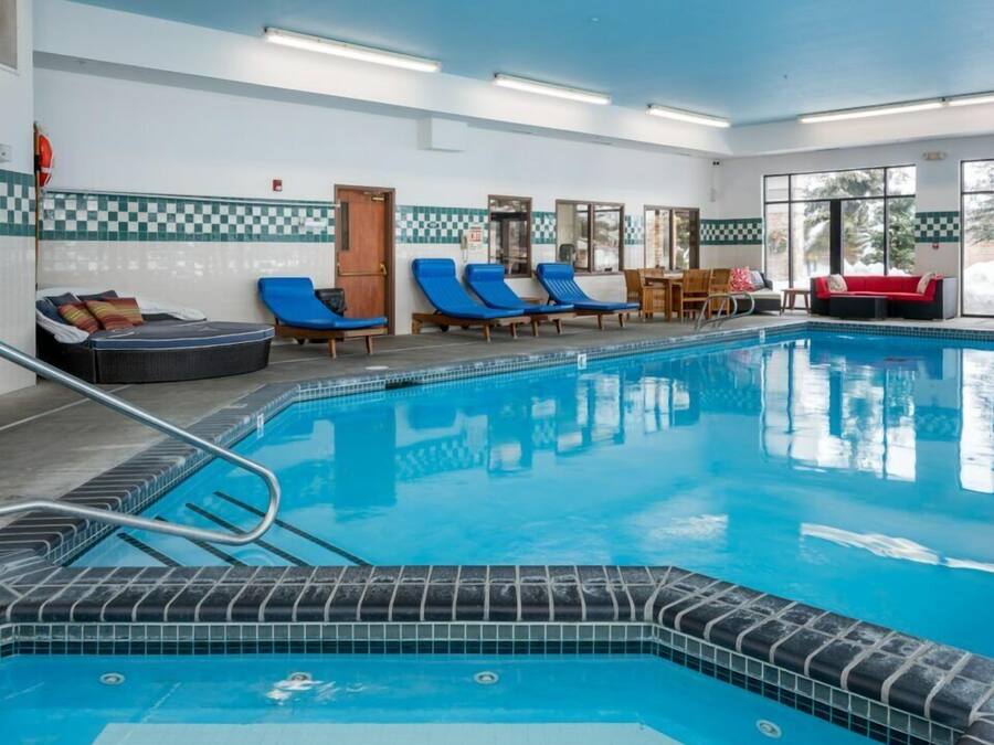 En indendørs swimmingpool med blå liggestole, en rød sofa og et skakmønstret vægdesign.