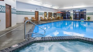 An indoor swimming pool with lounge chairs, a hot tub, and a checkered tile design on the walls. - Wood River Inn & Suites (Hailey)