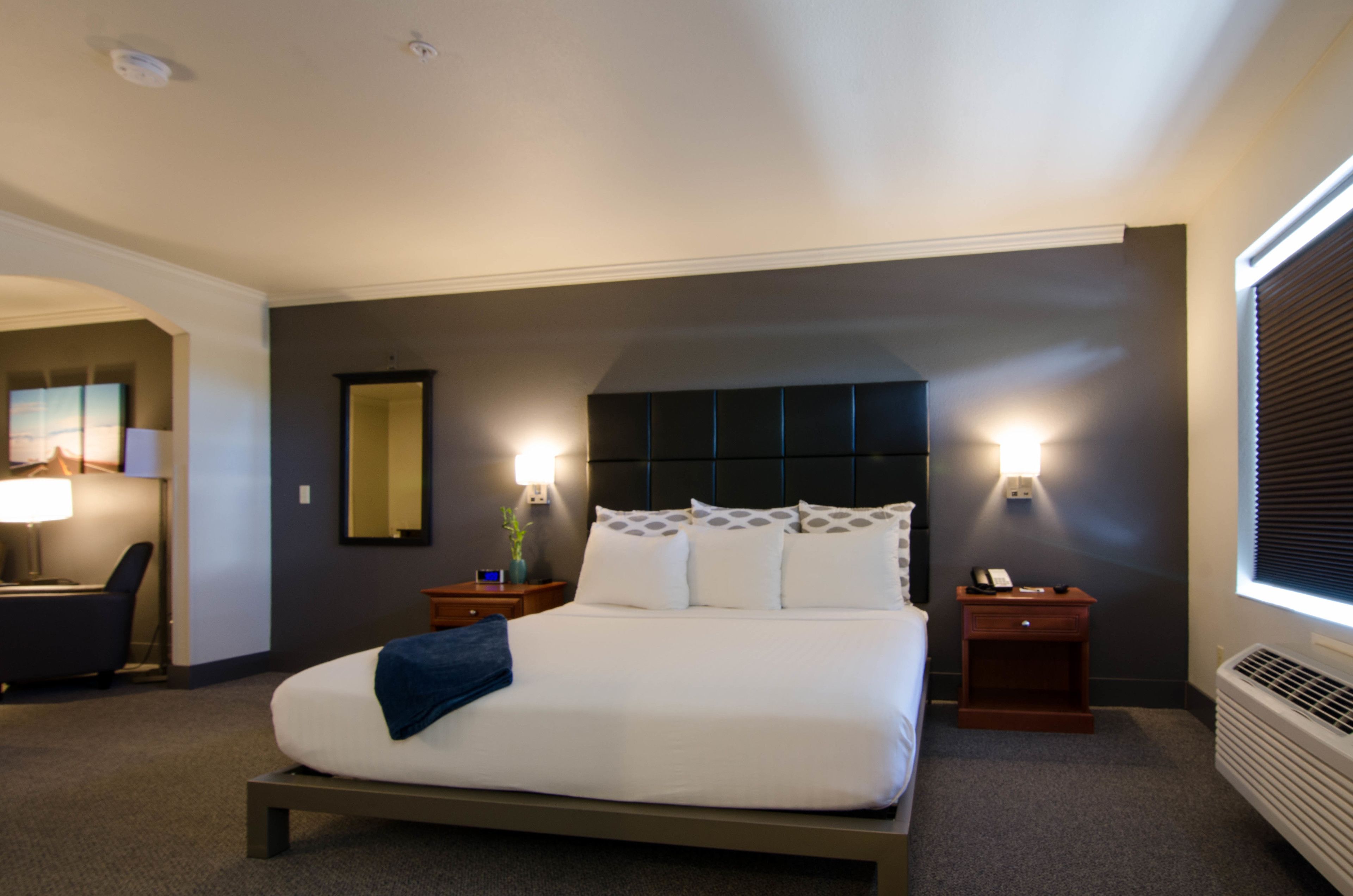 A hotel room with a large bed, bedside tables, a desk, and a chair.