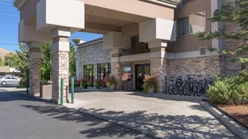 A hotel entrance with a covered walkway, stone pillars, and a bike parking area.