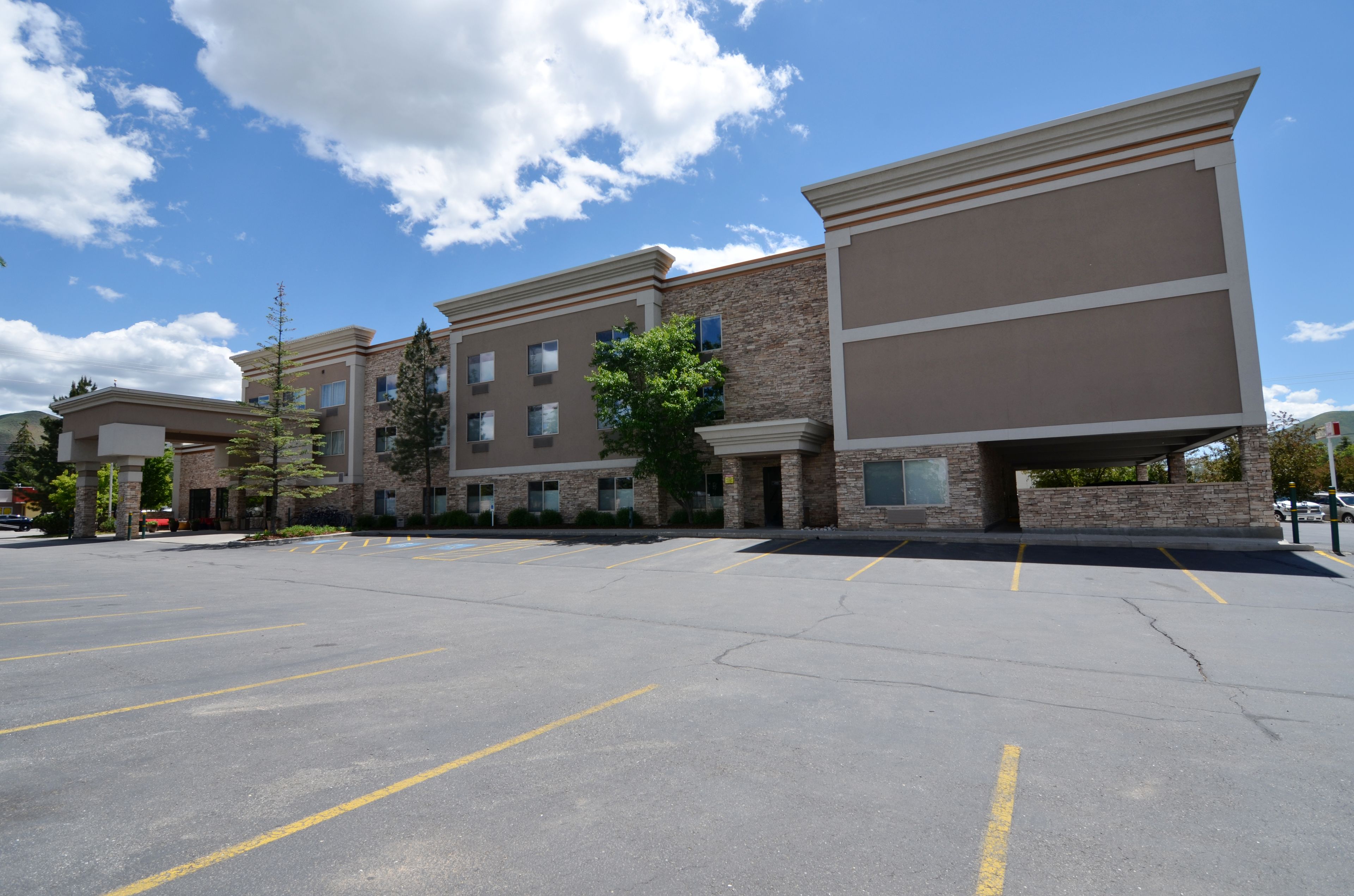 A multi-story hotel with a parking lot in front.