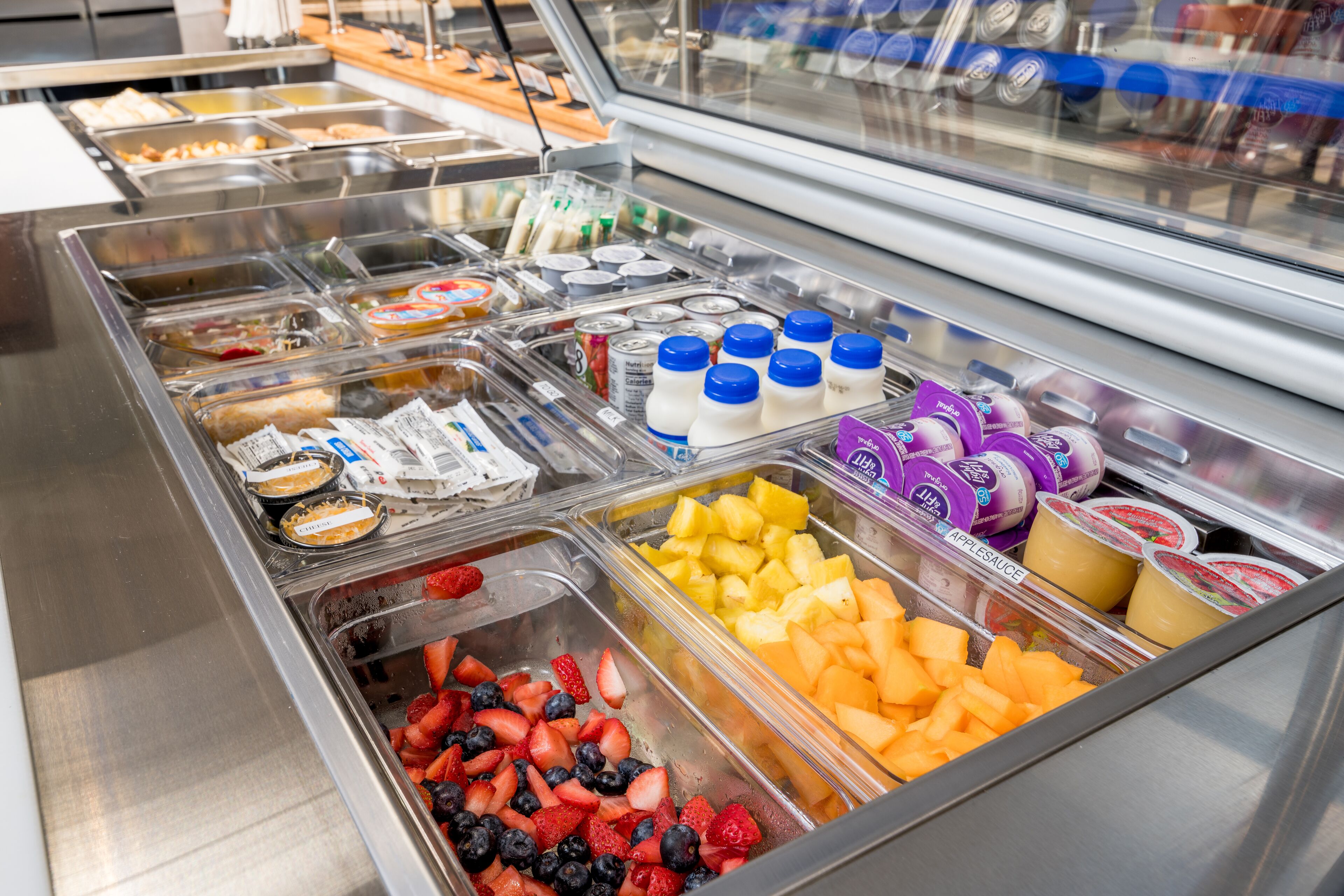 A buffet with various food options including fruits, yogurt, and sandwiches.