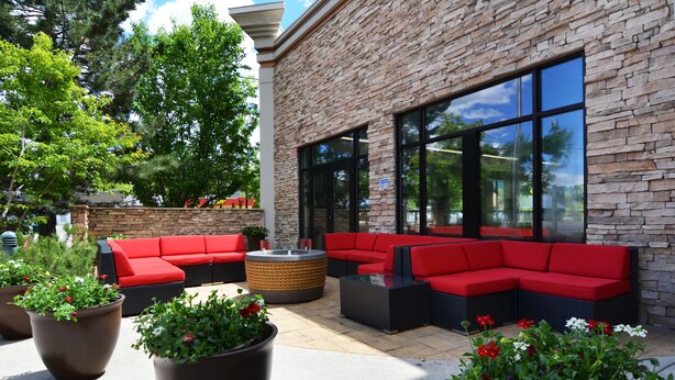 An outdoor seating area with red sofas and large planters. - Wood River Inn & Suites (Hailey)
