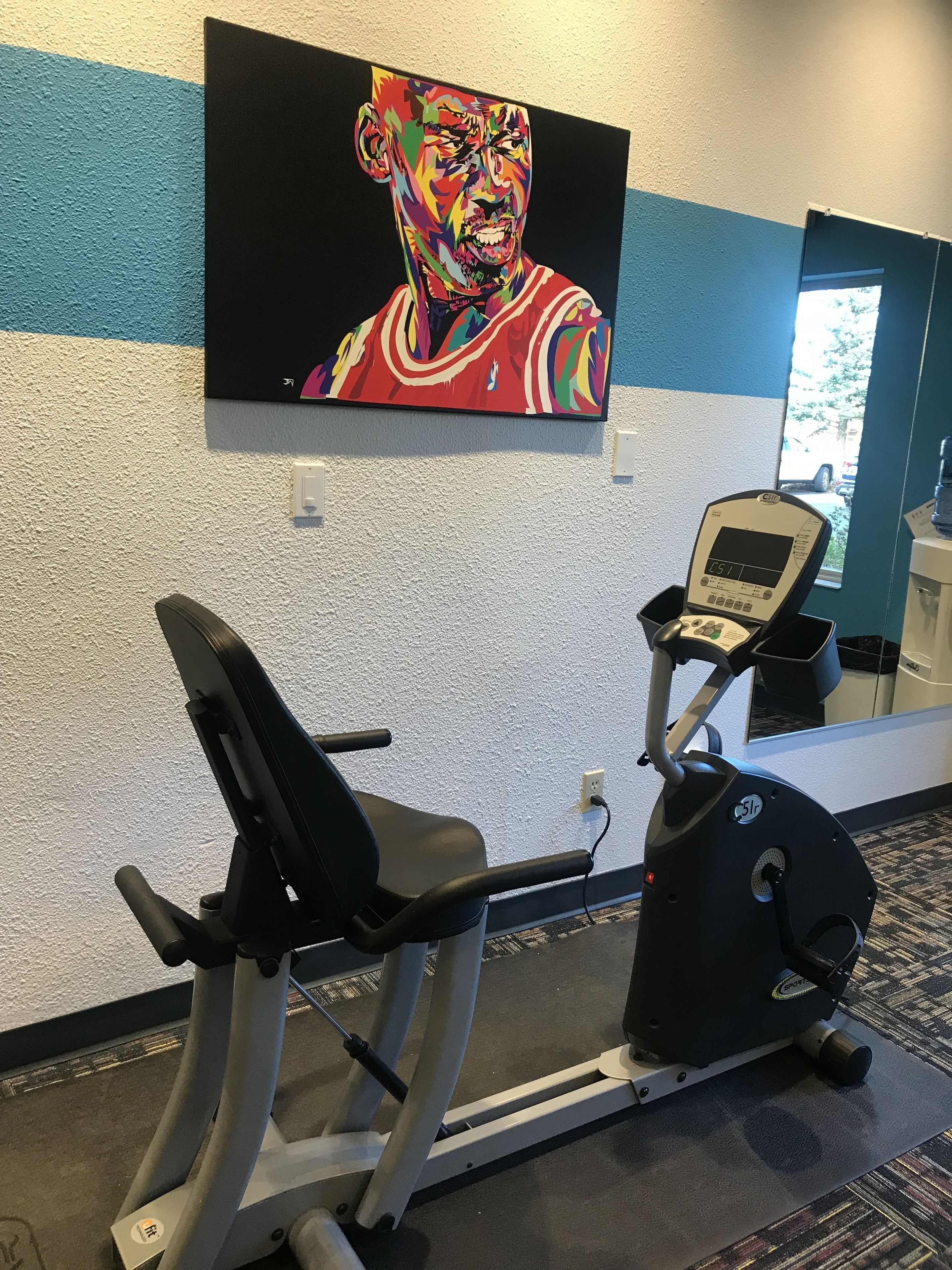 A gym with exercise equipment, a wall-mounted TV, and a water dispenser.