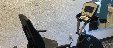 A gym with exercise equipment, a wall-mounted TV, and a water dispenser.