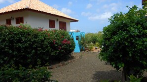 A house with a tiled roof, a blue door, and a gravel path leading to it. - West Hill Bungalows (Sabana Westpunt)