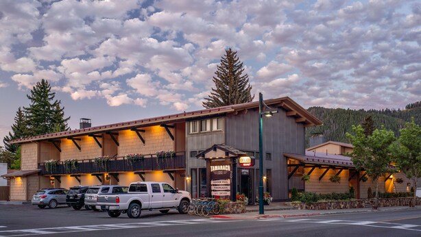 A building with a sign reading "Tamarack Lodge" and "Office" with a parking area in front. - Tamarack Lodge Sun Valley (Ketchum)