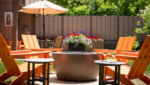 An outdoor patio with orange chairs, a round table, and a fire pit with flowers. - Tamarack Lodge Sun Valley (Ketchum)