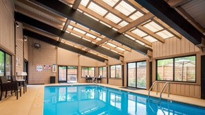 An indoor swimming pool with wooden beams, a poolside seating area, and large windows. - Tamarack Lodge Sun Valley (Ketchum)