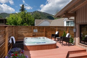 A hot tub on a wooden deck with chairs and a sign indicating a smoking area.
