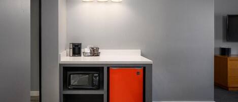 Una kitchenette compacta con microondas, refrigerador pequeño y cafetera.