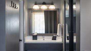 A bathroom with a vanity, a mirror, and a towel rack.