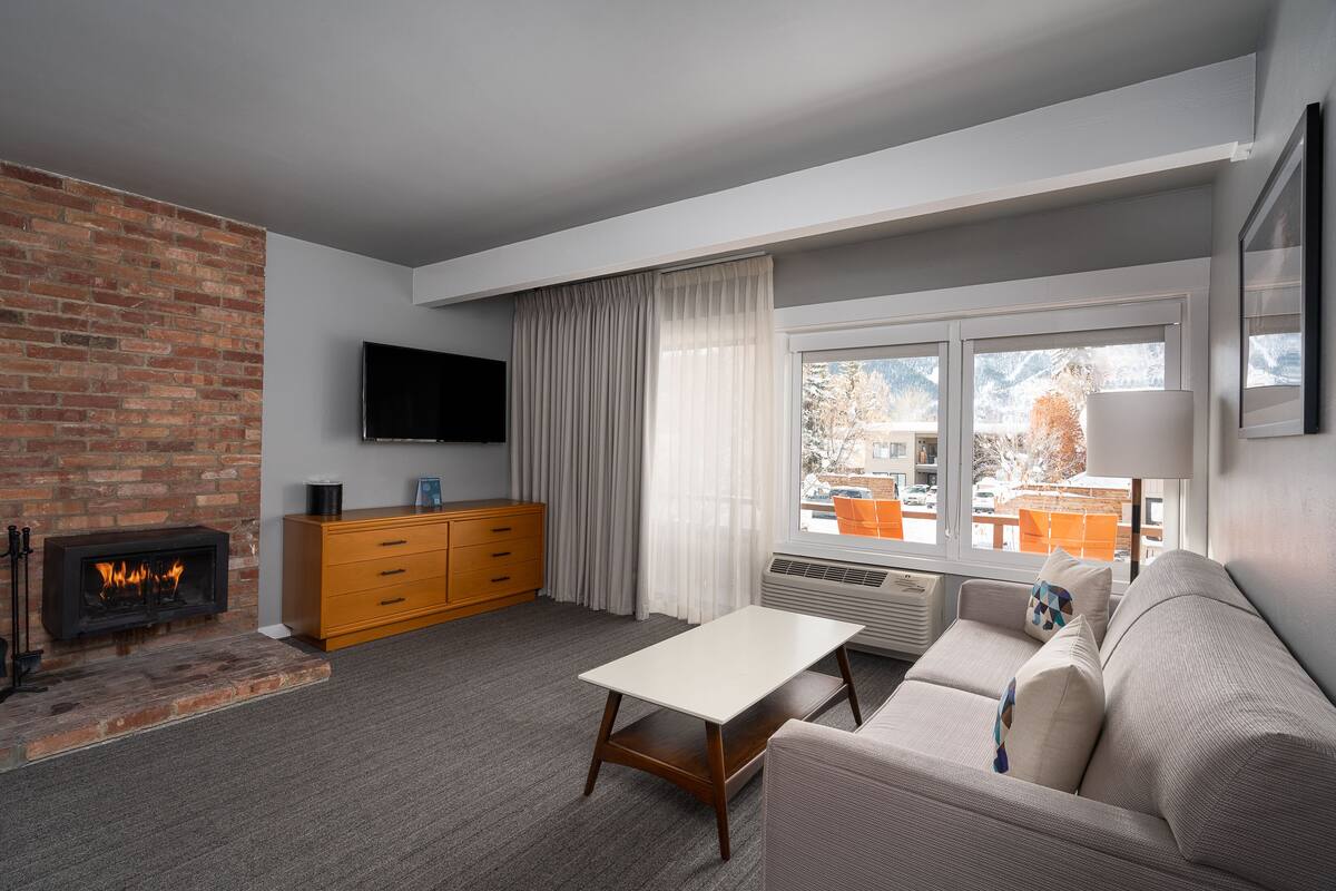 A modern living room with a fireplace, a flat-screen TV, a sofa, and a dining table.