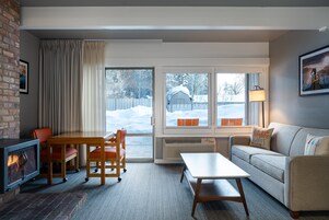 A cozy living room with a fireplace, a sofa, a table, and chairs.