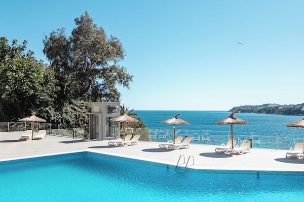 Una piscina al aire libre de temporada, sombrillas