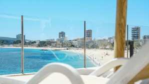 A beach view with a clear sky, a sandy beach, and a cityscape in the background. - Bahia Principe Escape Coral Playa – Adults Only 16+ (Calvia)