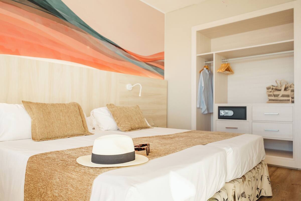 Una habitación de hotel con una cama, un armario y una pared con diseño ondulado.