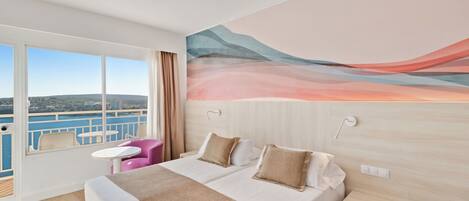 Habitación de hotel con una cama grande, una mesita, una silla y vista al mar.